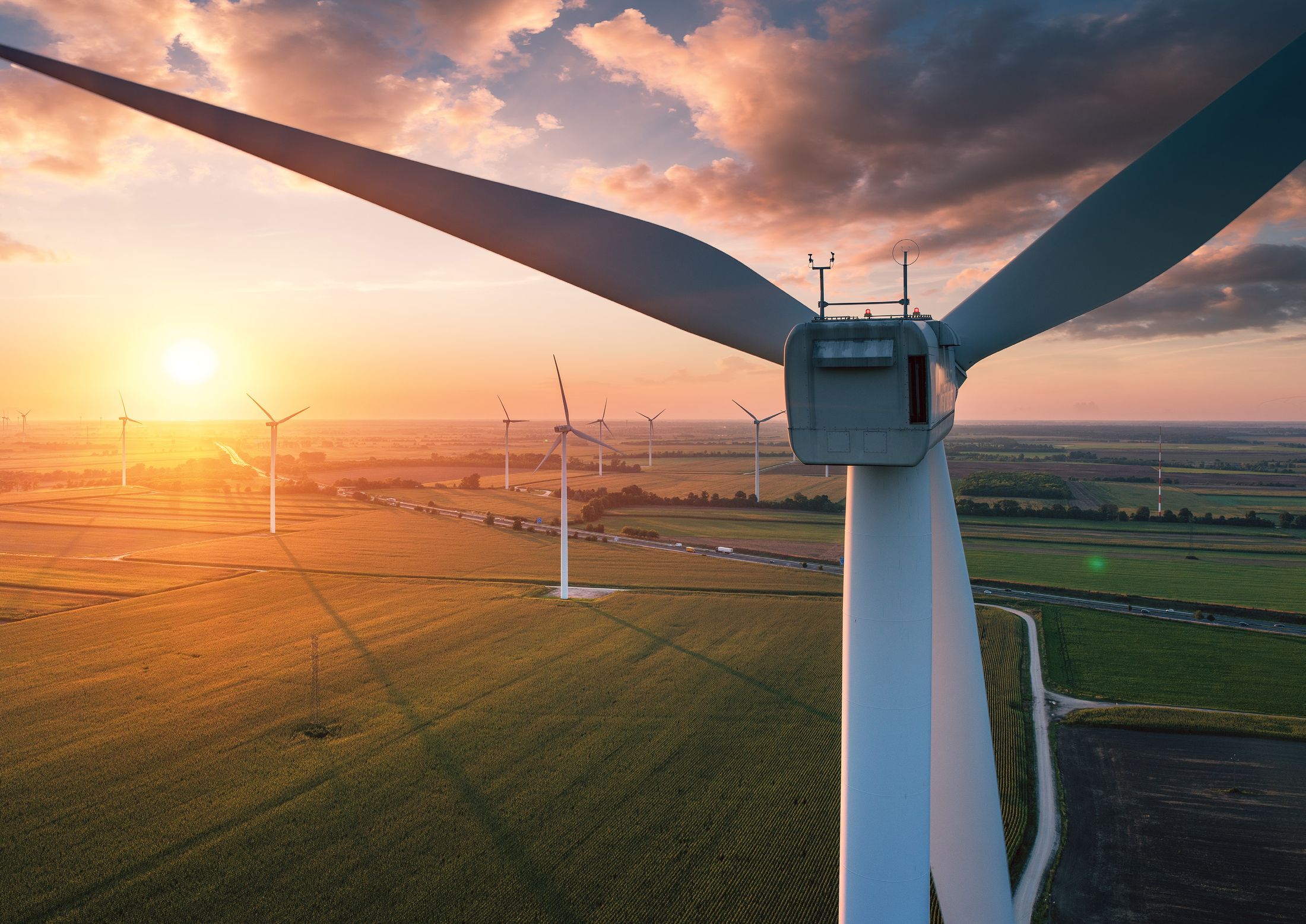A wind turbine above fields at sunset