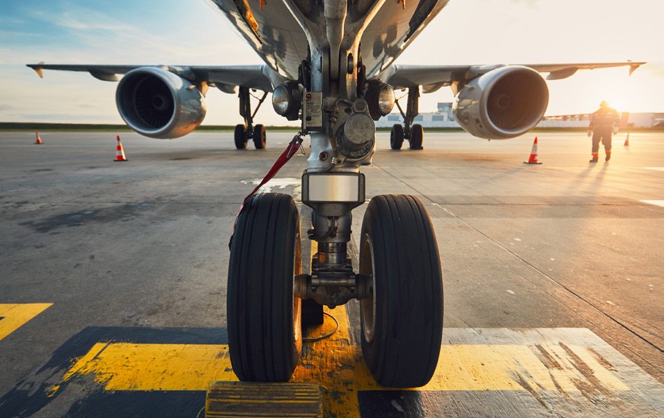 An airliner&rsquo;s landing gear on the runway at sunset