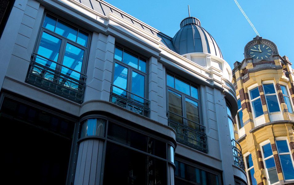 A modern glass building next to a historic facade