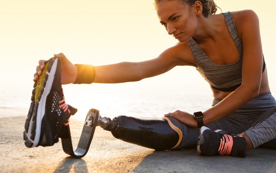An athlete with a running blade stretching at sunrise